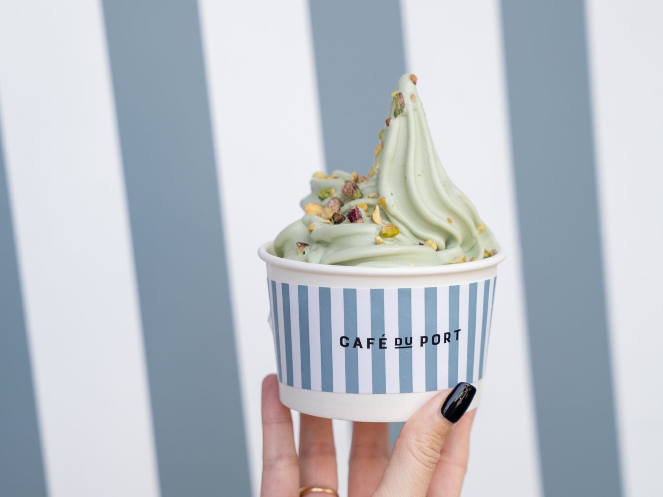 discover-our-sweet-treat-4x3 Hand holding a striped Café du Port cup of pistachio soft serve